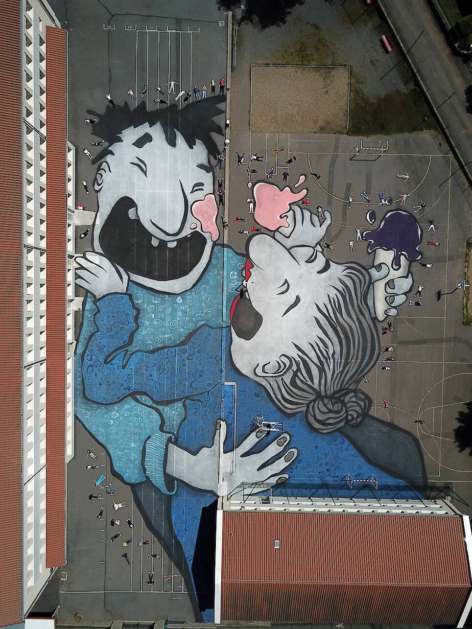 an aerial view of a large mural by Ella & Pitr on the ground of a public square featuring a cartoonish pair of laughing figures