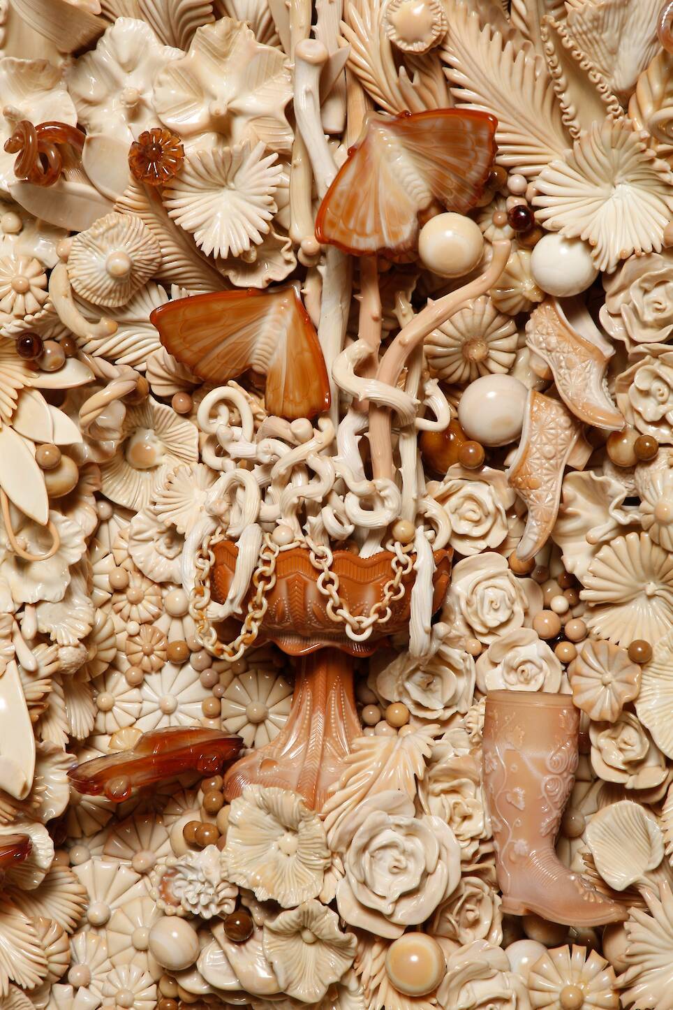 a detail of a brown milkglass piece with flowers, butterflies, jewels, and other baubles