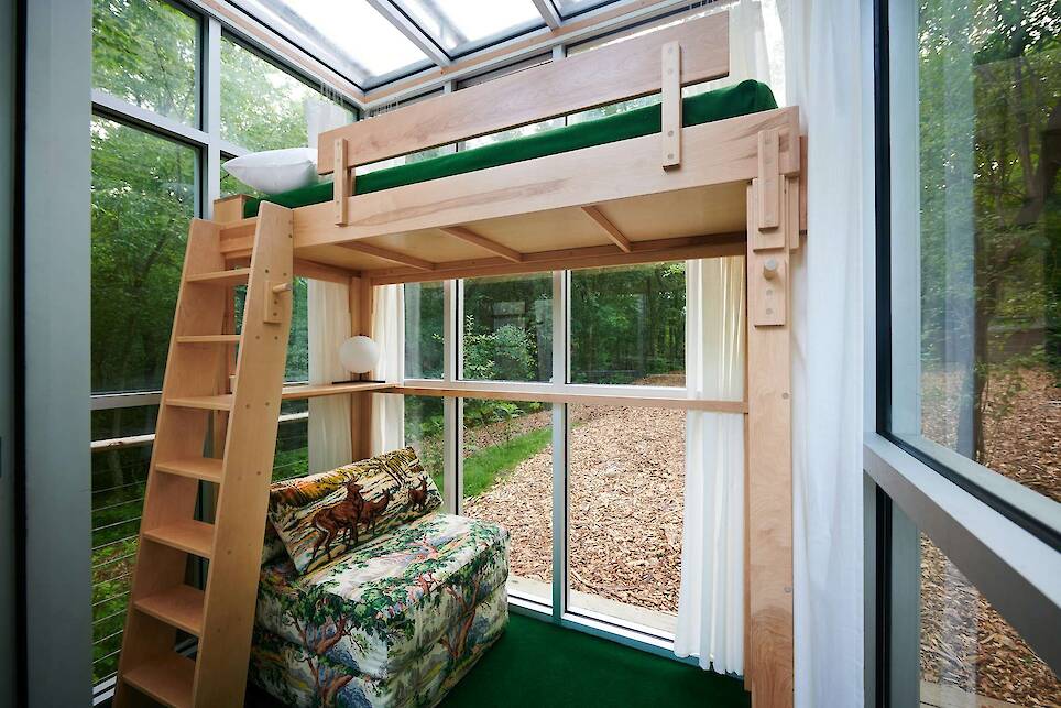 One of the cabins has a lofted bed and a seating area below. Sheers provide privacy to the interiors as needed