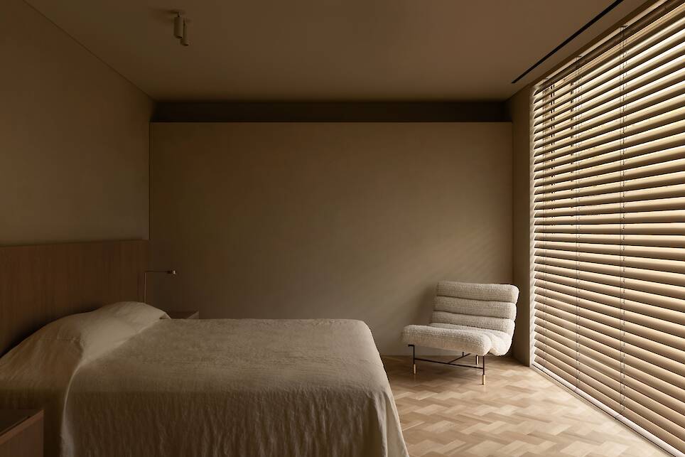 Minimalist, neutral bedroom with blinds at window
