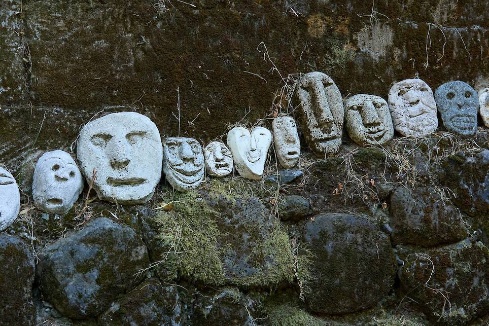 a series of concrete face sculptures lined up outside in the Northern California woods