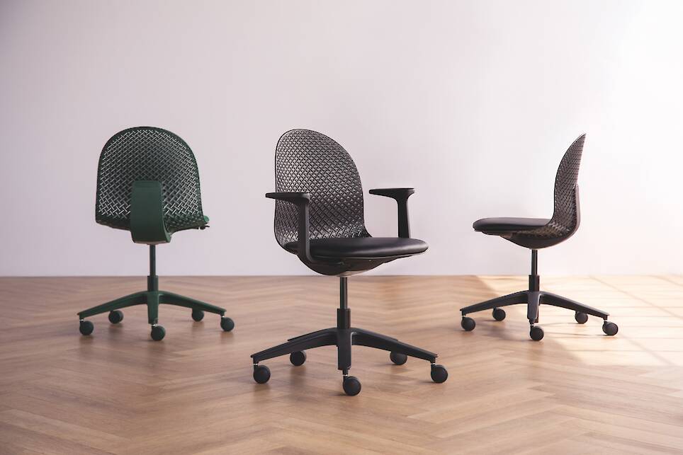 Three modern office chairs with mesh backs and wheeled bases are placed on a wooden floor against a plain light-colored wall