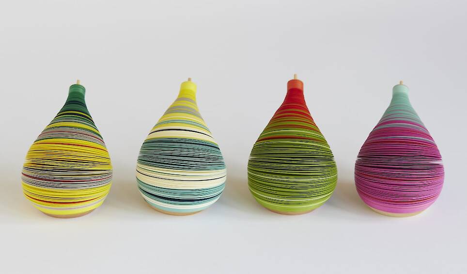 a series of small paper figures made from numerous layers of colored paper on a flexible central axis so that they look like anthropomorphized pears