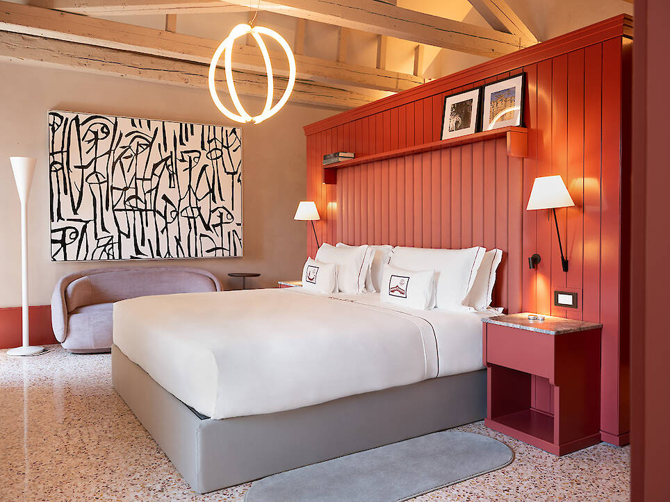 Modern bedroom with a king bed, red paneled wall, abstract black and white artwork, two wall lamps, and contemporary decor inspired by the refined elegance of Elizabeth Unique V