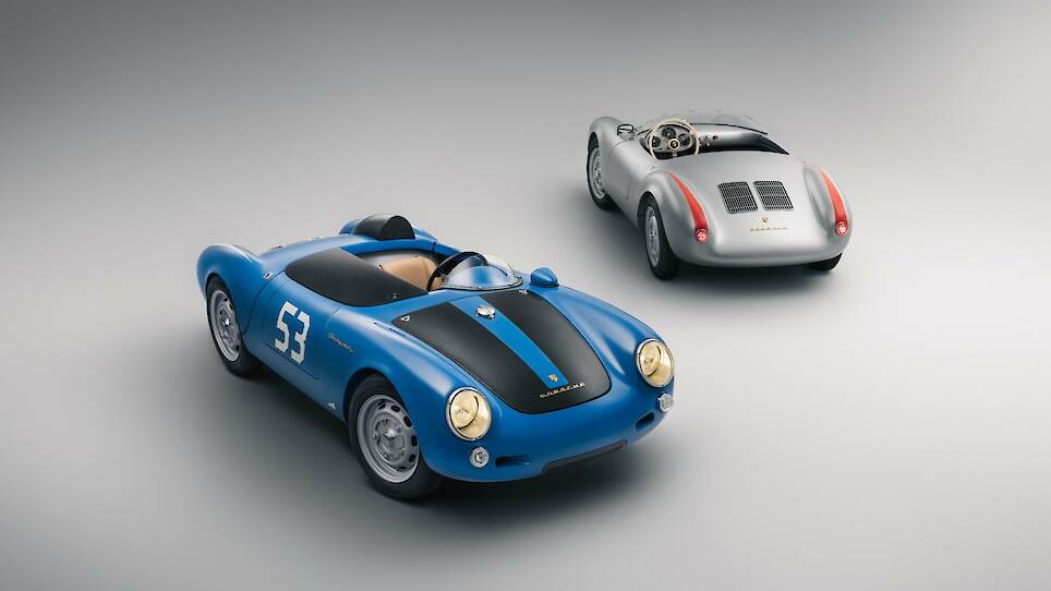 Two vintage Porsche sports cars, including a striking silver Porsche 550 J and a blue model with black racing stripes and the number 53, are displayed on a plain grey background