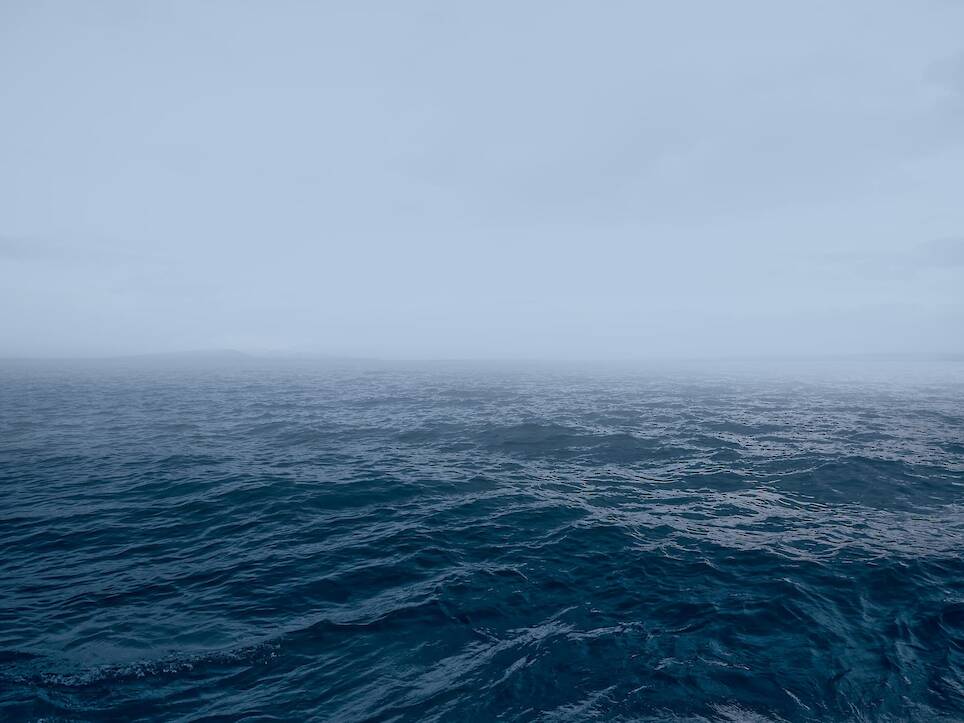 an open body of water with fog in the distance