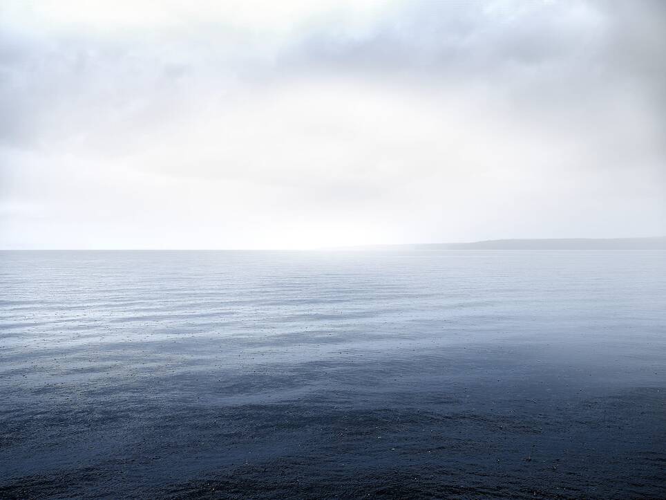 an open body of water during the early morning with light clouds in the sky