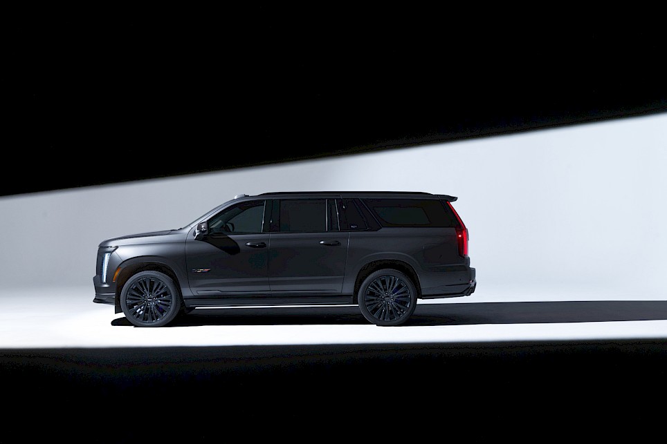 Side profile of a black Cadillac Escalade-V 125th Anniversary SUV against a high-contrast diagonal light background