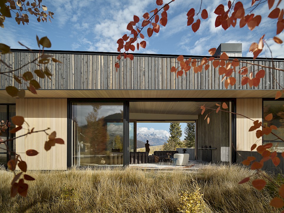 Modern home with large glass sliding doors opening to a living area, framing a mountain view beyond