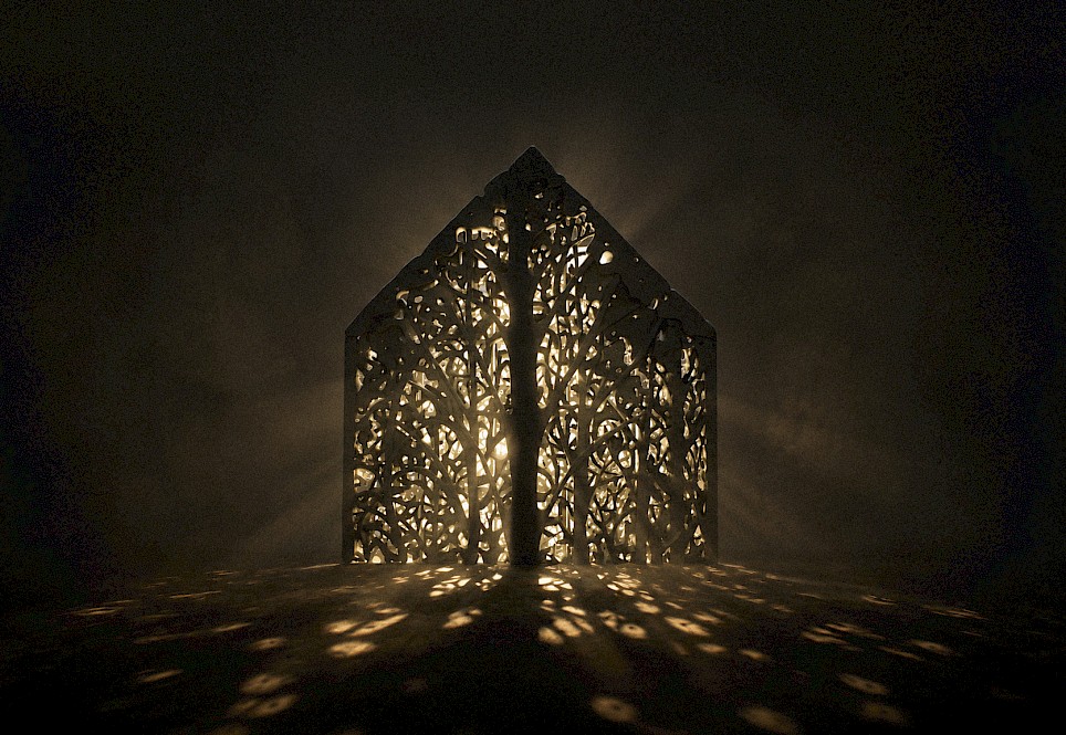 A house-shaped structure with intricate, tree-like cutouts glowing with light from within